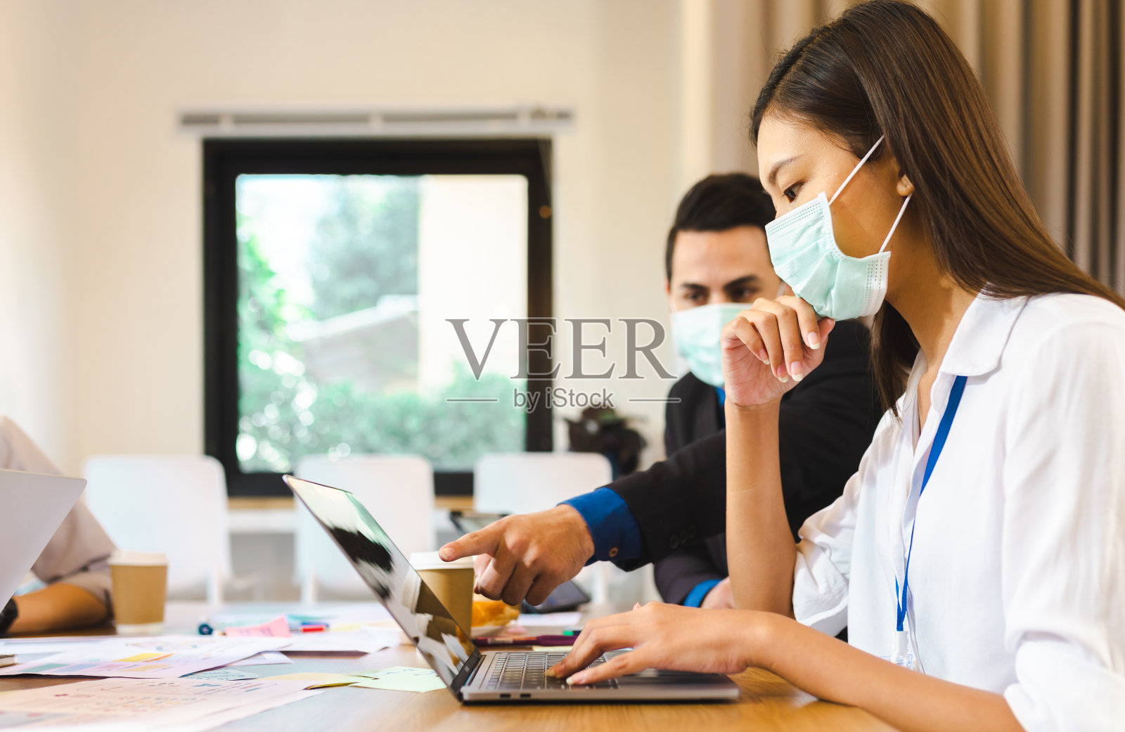 一群年轻的亚洲企业家在讨论。亚洲年轻企业家们在新冠病毒后进行头脑风暴会议、共享数据和戴着口罩的玻璃墙工作。照片摄影图片