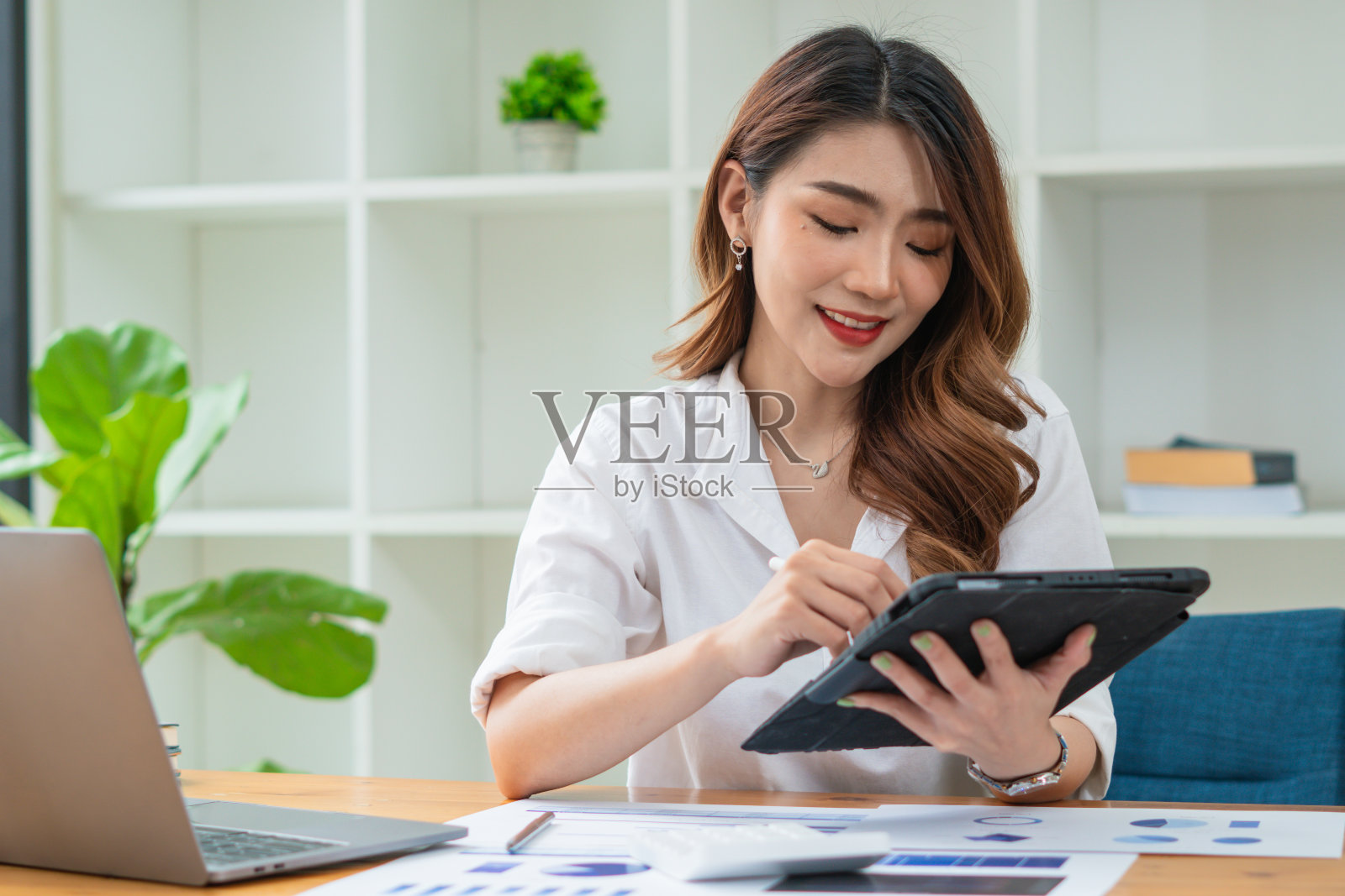 年轻的亚洲女商人用平板电脑微笑的脸，积极的情绪，在办公室，休闲的办公室生活理念照片摄影图片