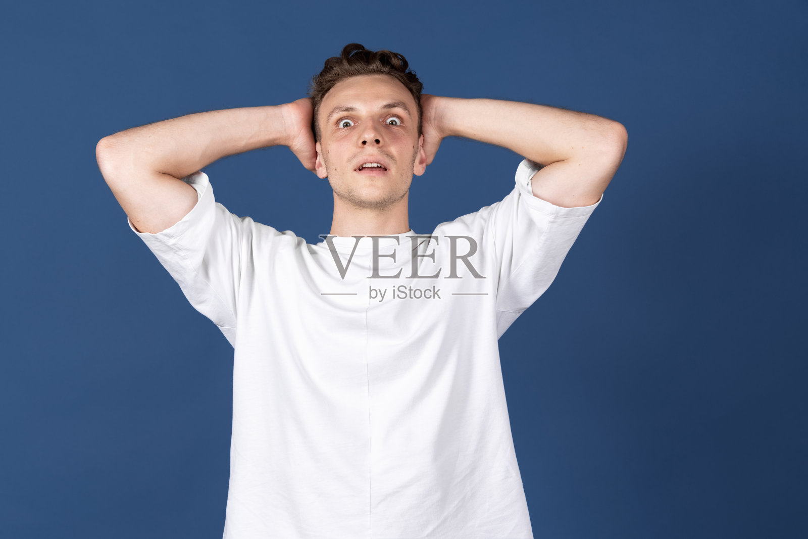 一个白人年轻男子被隔离在藏青色的工作室背景下。概念人类的情感，面部表情，青春，感情，广告。照片摄影图片