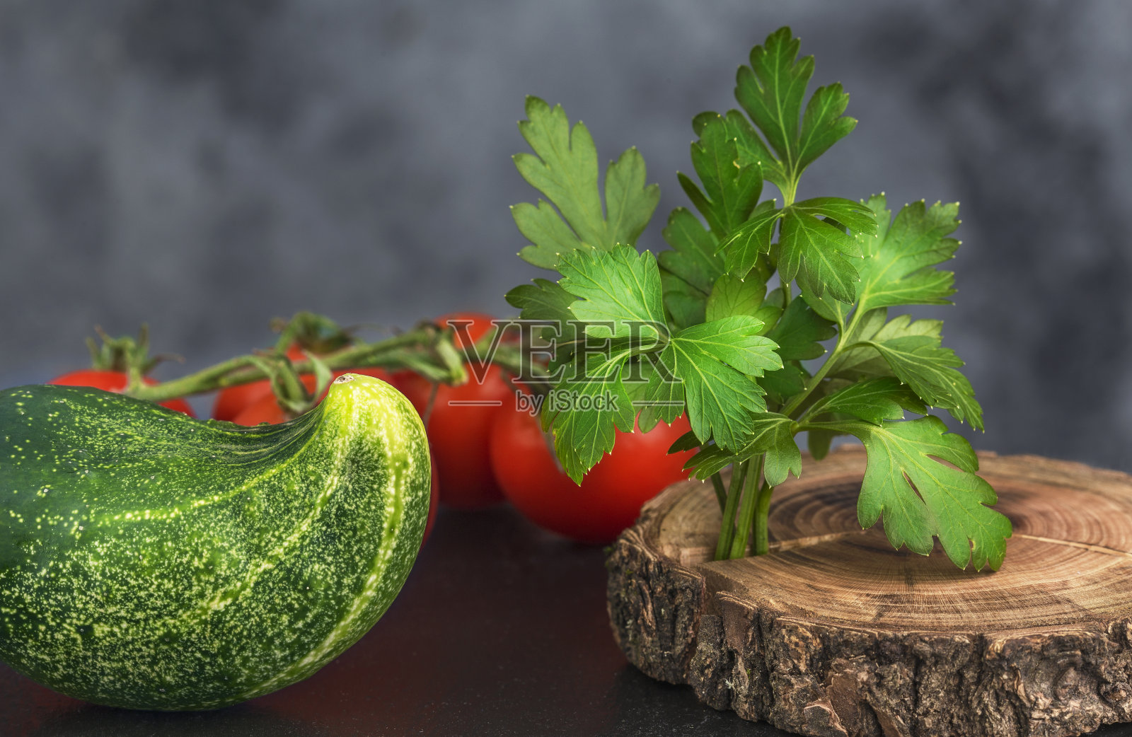 一块木板上有红番茄、绿黄瓜和绿欧芹的枝条照片摄影图片