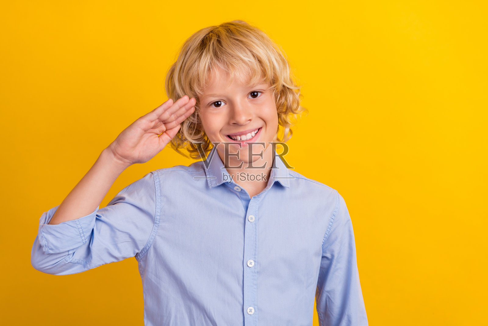 照片中可爱的小男孩身穿蓝色衬衫，以黄色为背景照片摄影图片