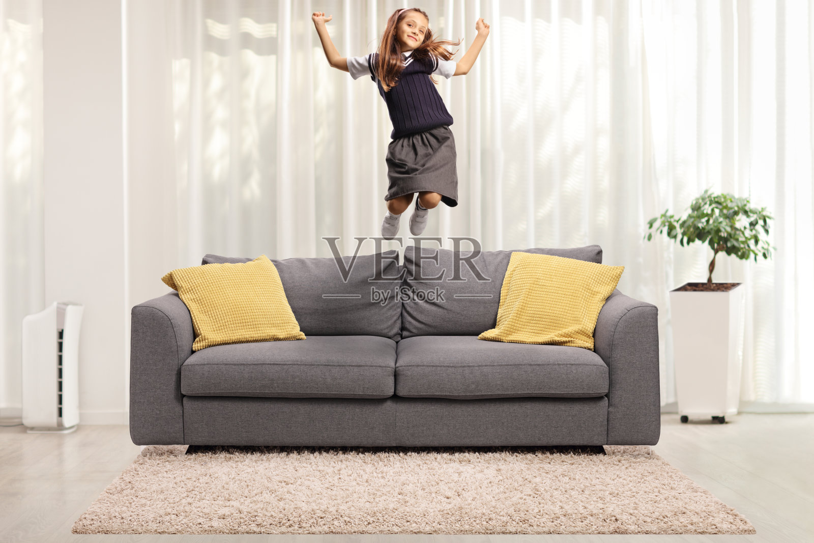 兴奋的女学生穿着校服在家里的沙发上跳来跳去照片摄影图片