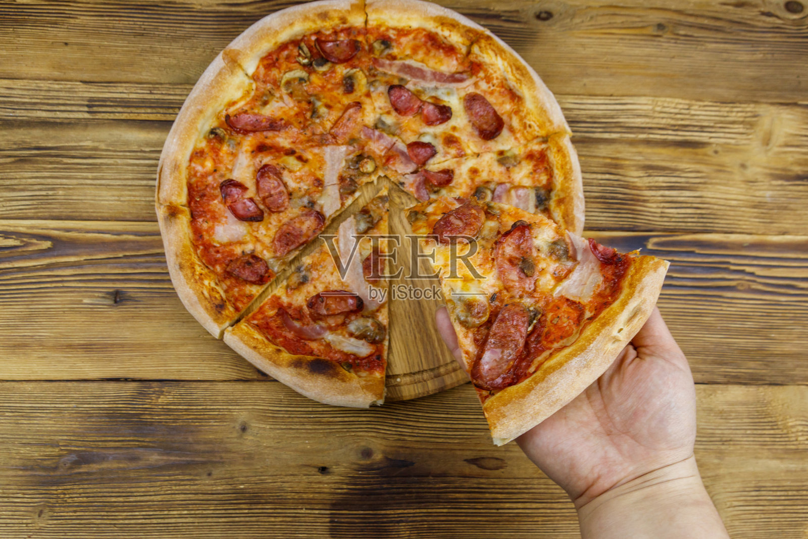 手拿着一片美味的披萨。木桌上的热意大利披萨。俯视图照片摄影图片