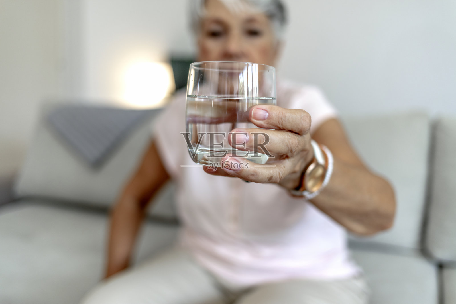 近中年妇女端着玻璃杯喝静水享受健康生活习惯。照片摄影图片