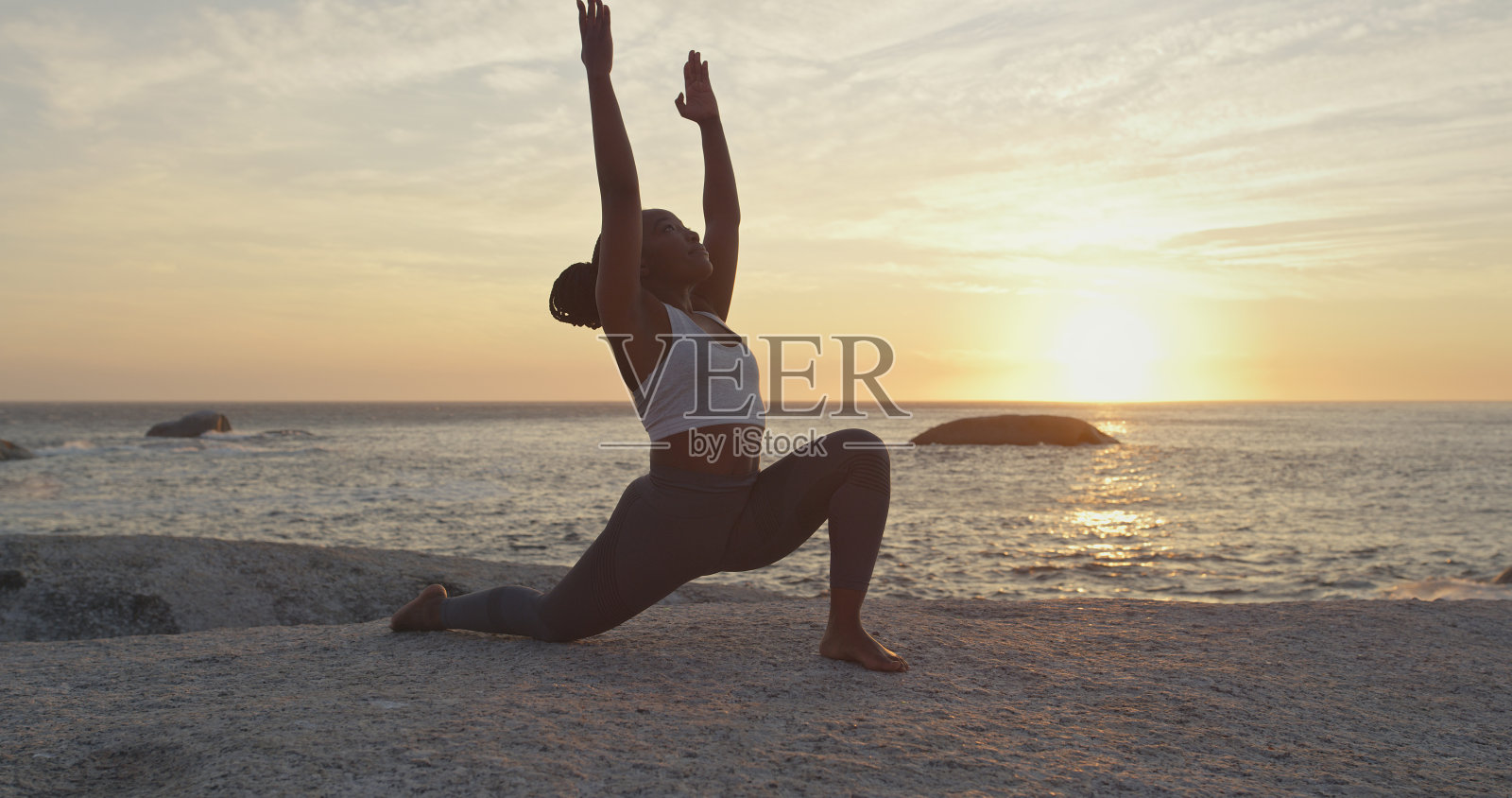 一个有吸引力的年轻女人在日落的海滩上练习瑜伽的全长镜头照片摄影图片