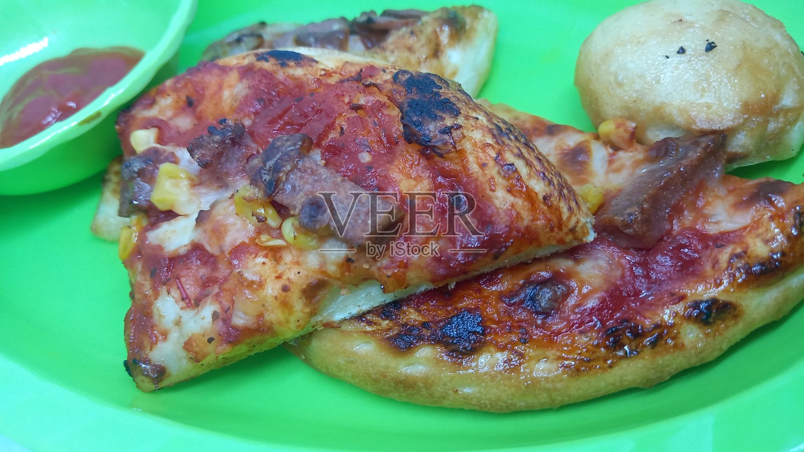 在绿色的三聚氰胺盘子上自制的香肠披萨照片摄影图片