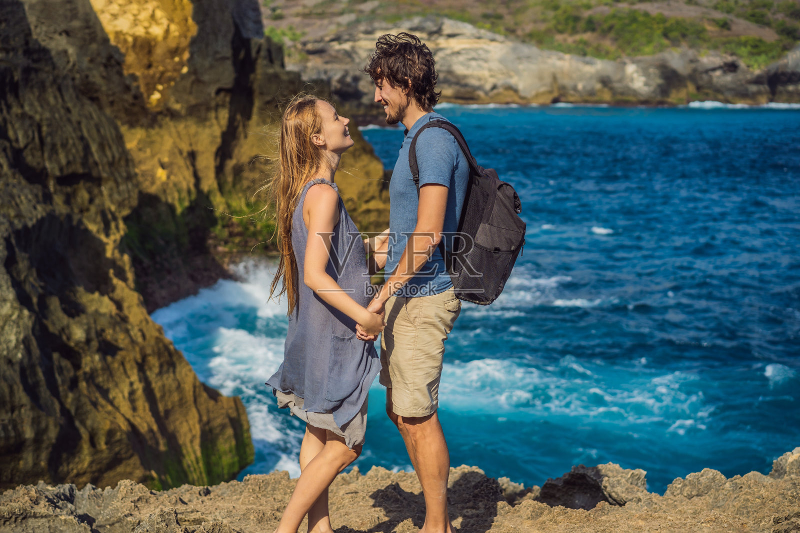 在印度尼西亚巴厘岛的努沙佩尼达，一男一女游客在海天使的比拉邦的背景下度蜜月。巴厘岛旅游的概念照片摄影图片