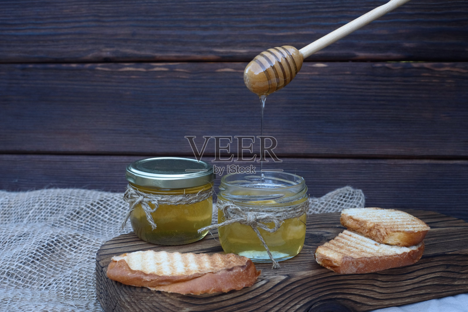新鲜芬芳的蜂蜜装在玻璃罐里，桌上是木制背景。不同种类的蜂蜜。自然产品。照片摄影图片