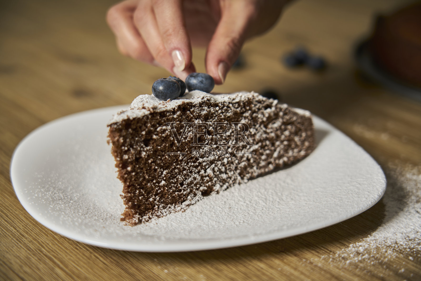 一位女士正在装饰一块手工制作的巧克力蛋糕。照片摄影图片