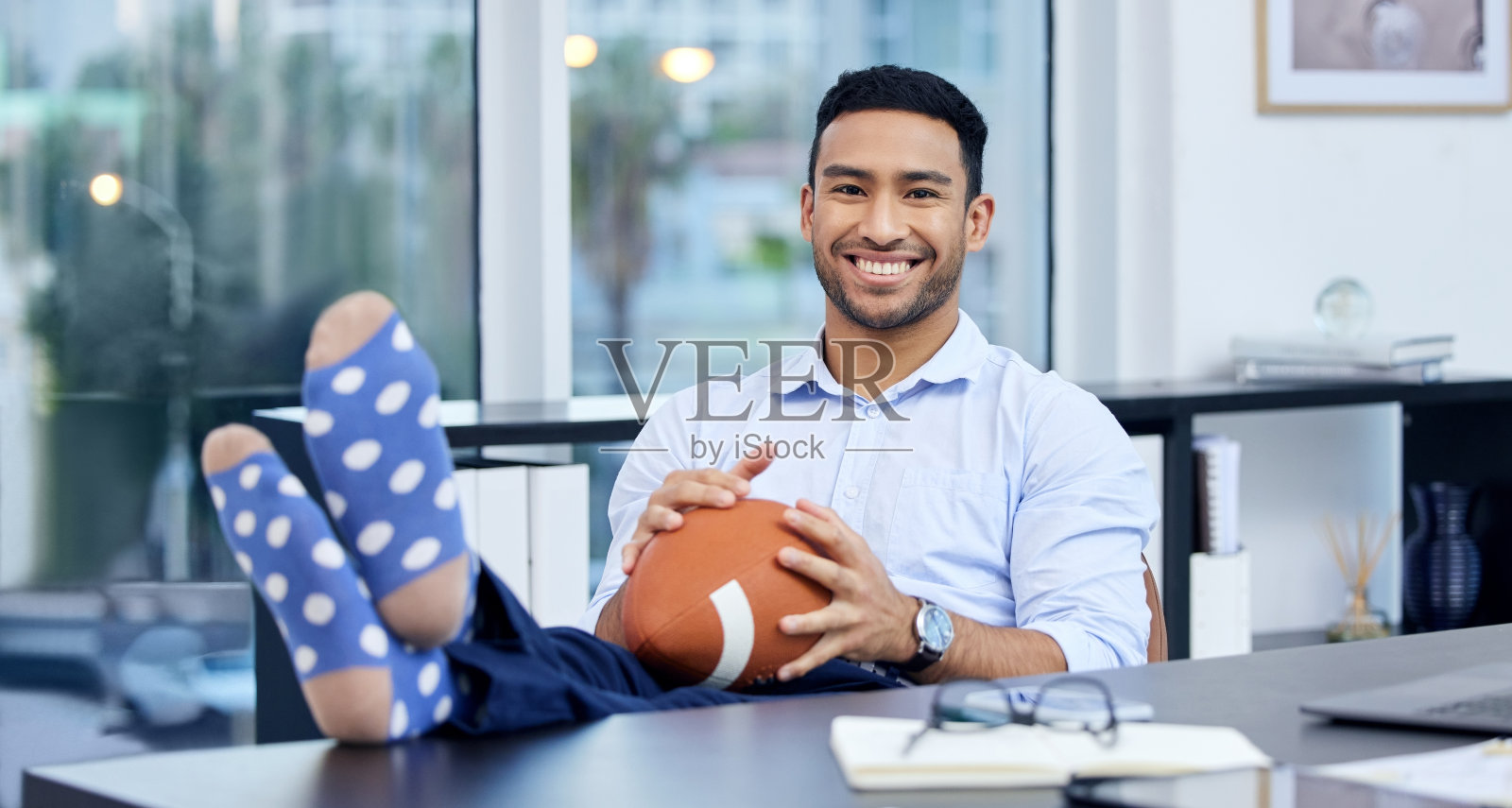 一个年轻的商人在他的办公桌前拿着一个球照片摄影图片