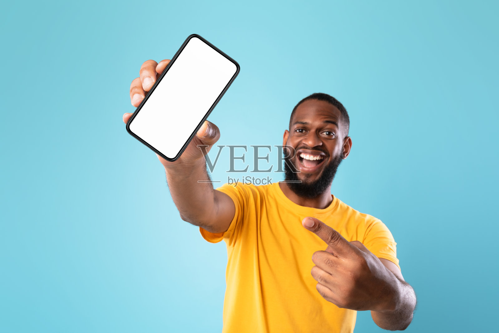 一个黑色的家伙指着蓝色背景黑屏的智能手机，模型照片摄影图片