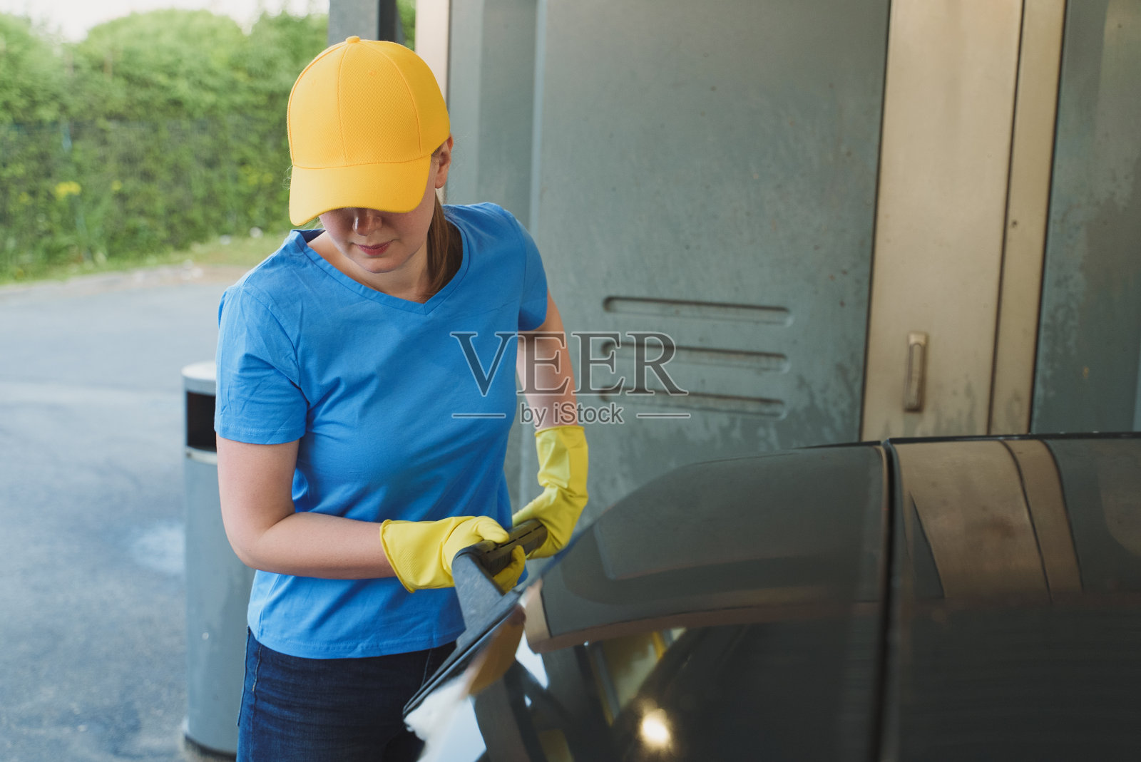 穿着制服的女人用刷子清洗汽车。洗车服务。照片摄影图片