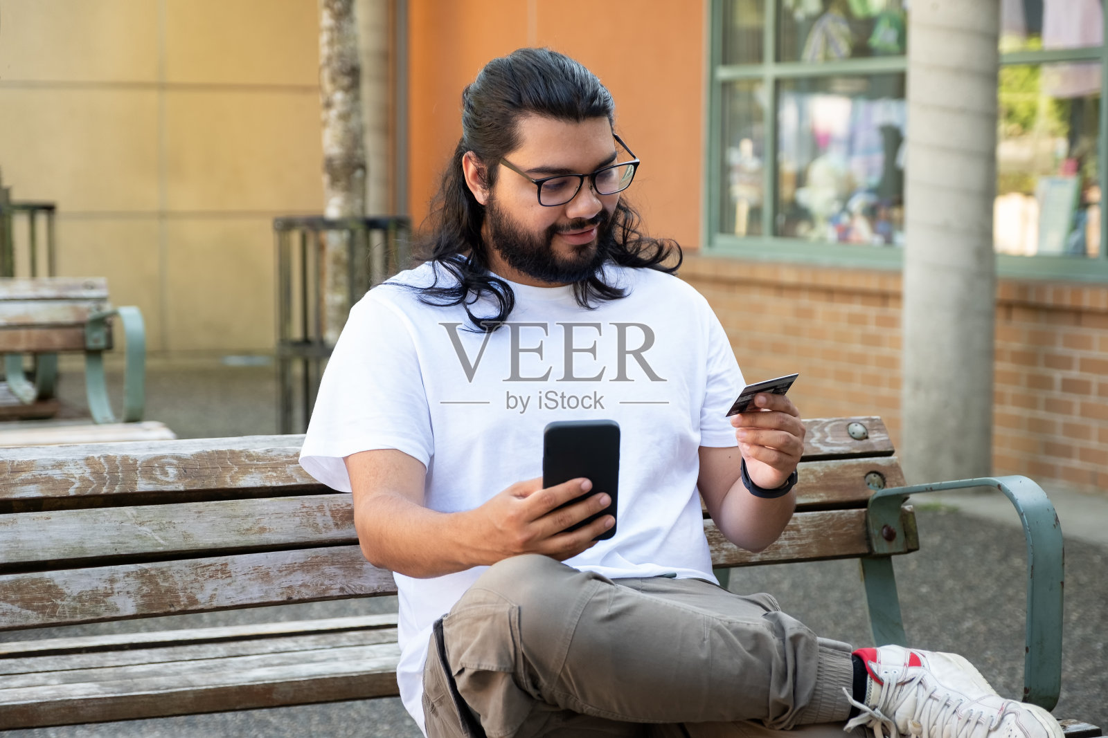 西班牙裔年轻人用智能手机和信用卡在网上购物照片摄影图片