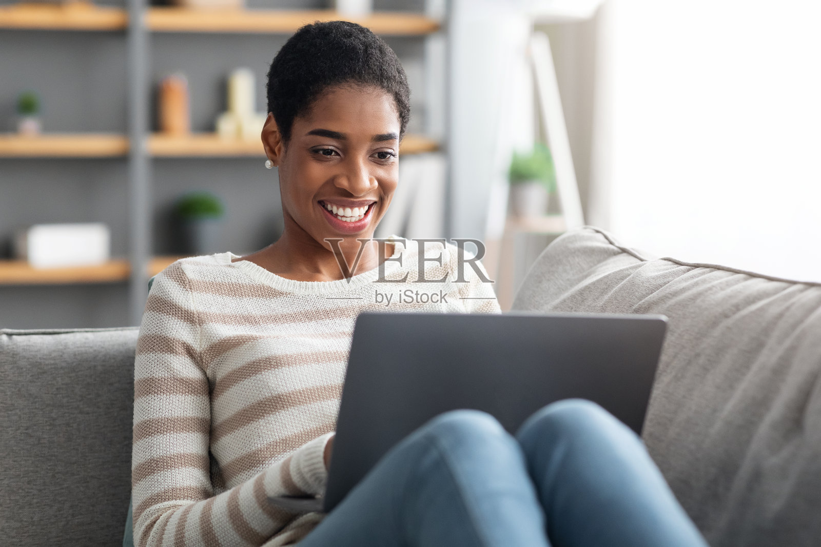 快乐的黑人女性浏览笔记本电脑而放松在家里照片摄影图片