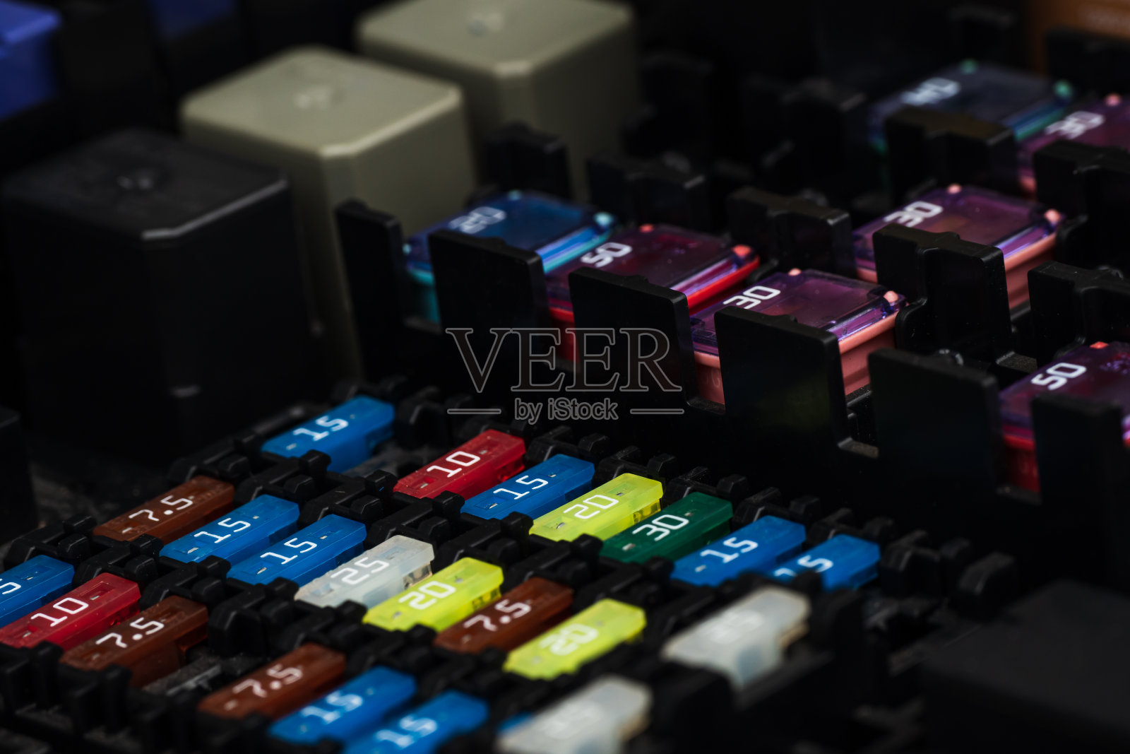 汽车保险丝在一个黑色的面板上，带有支架和多色标记。这是一个保护装置，当电路中的额定电流超过时，它会打开电路。电气维修。照片摄影图片