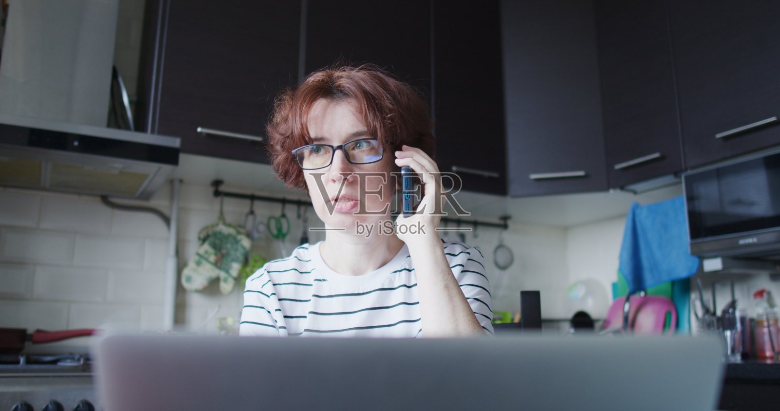 一个在厨房餐桌上工作的成熟女人的肖像照片摄影图片