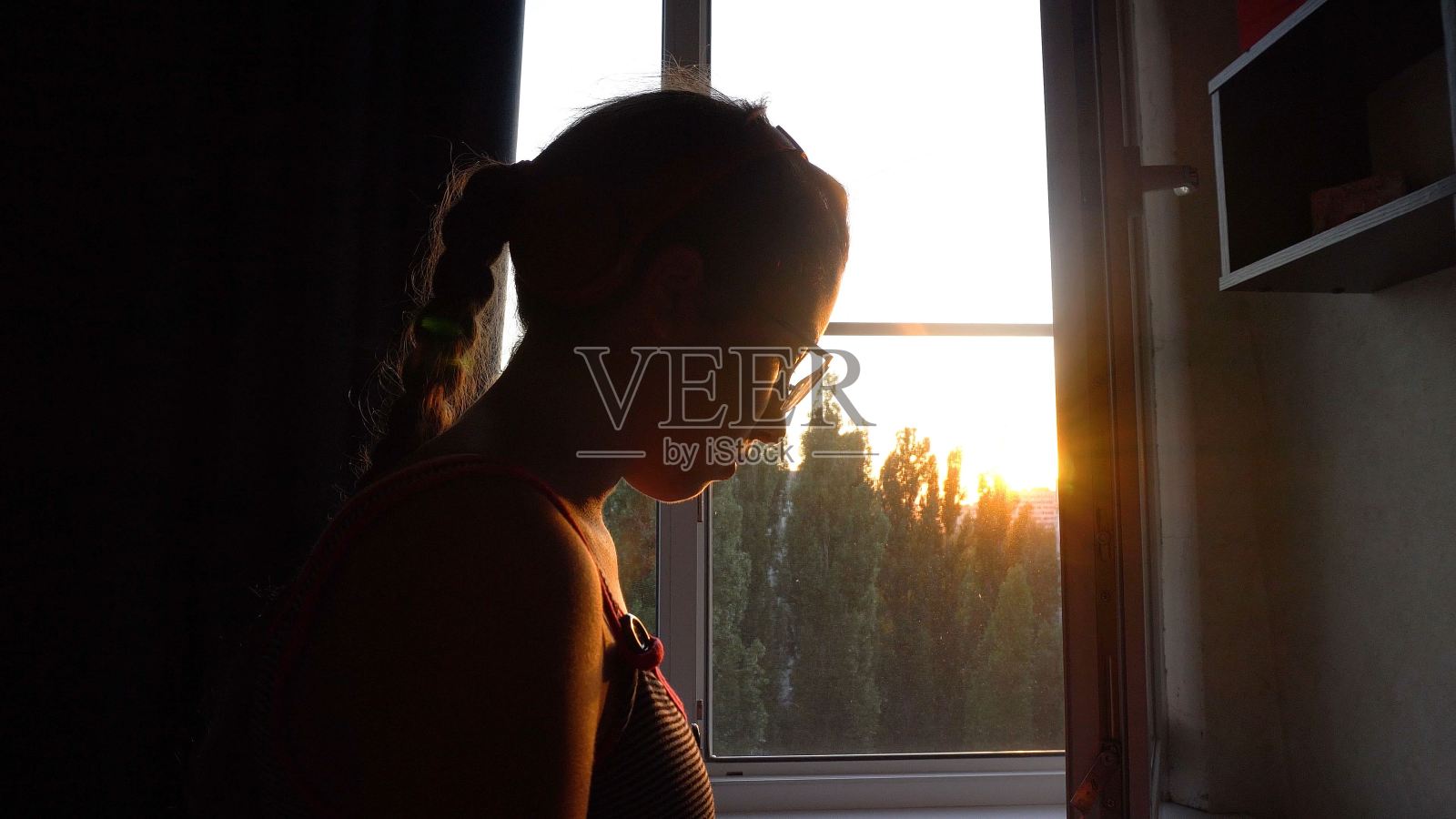 一个戴眼镜的少女站在窗边照片摄影图片