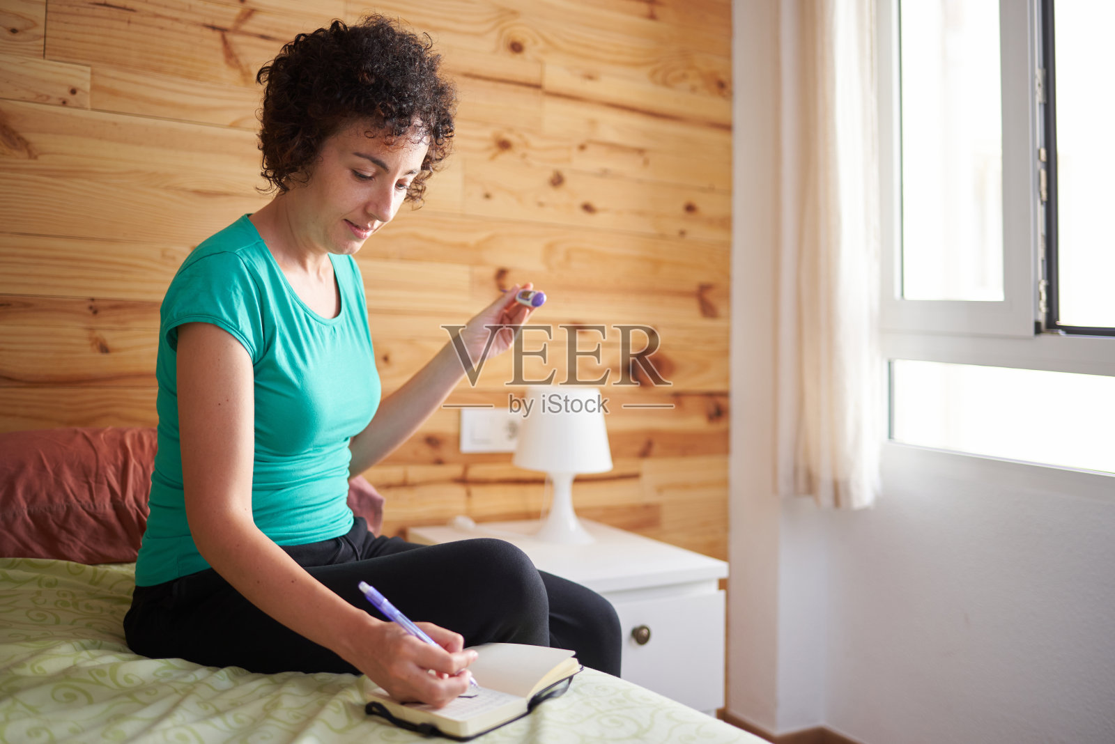 一个女人在她的笔记本上写下她的基础温度计测量的温度照片摄影图片