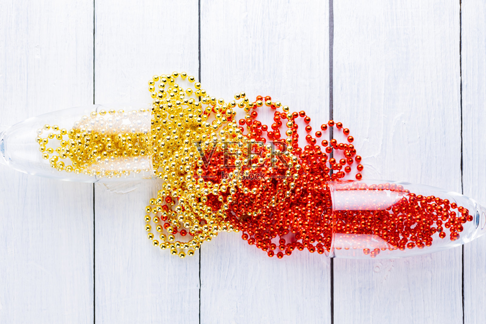 白色背景上有圣诞珠子的香槟杯。木板上的圣诞装饰。副本的空间。俯视图照片摄影图片