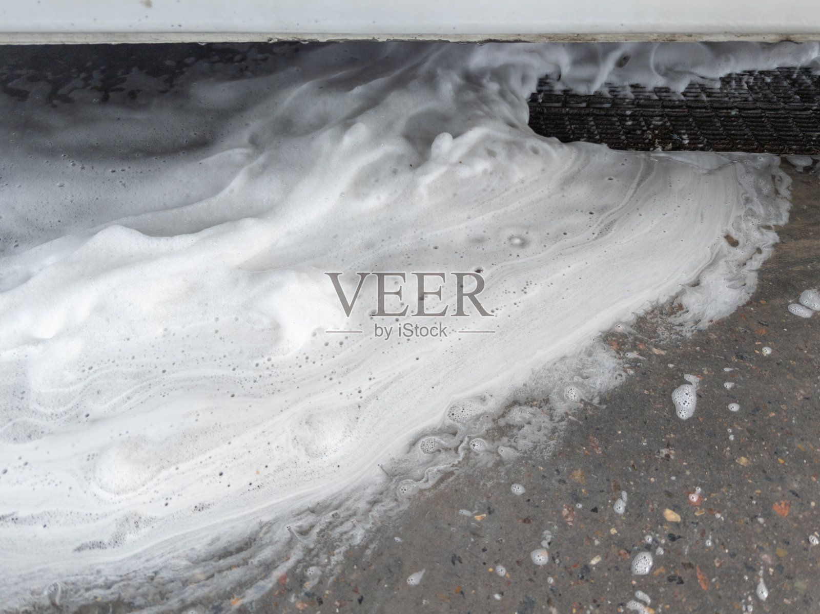 肥皂和垃圾流到洗车车库的地漏网格。全帧特写与选择性聚焦。照片摄影图片