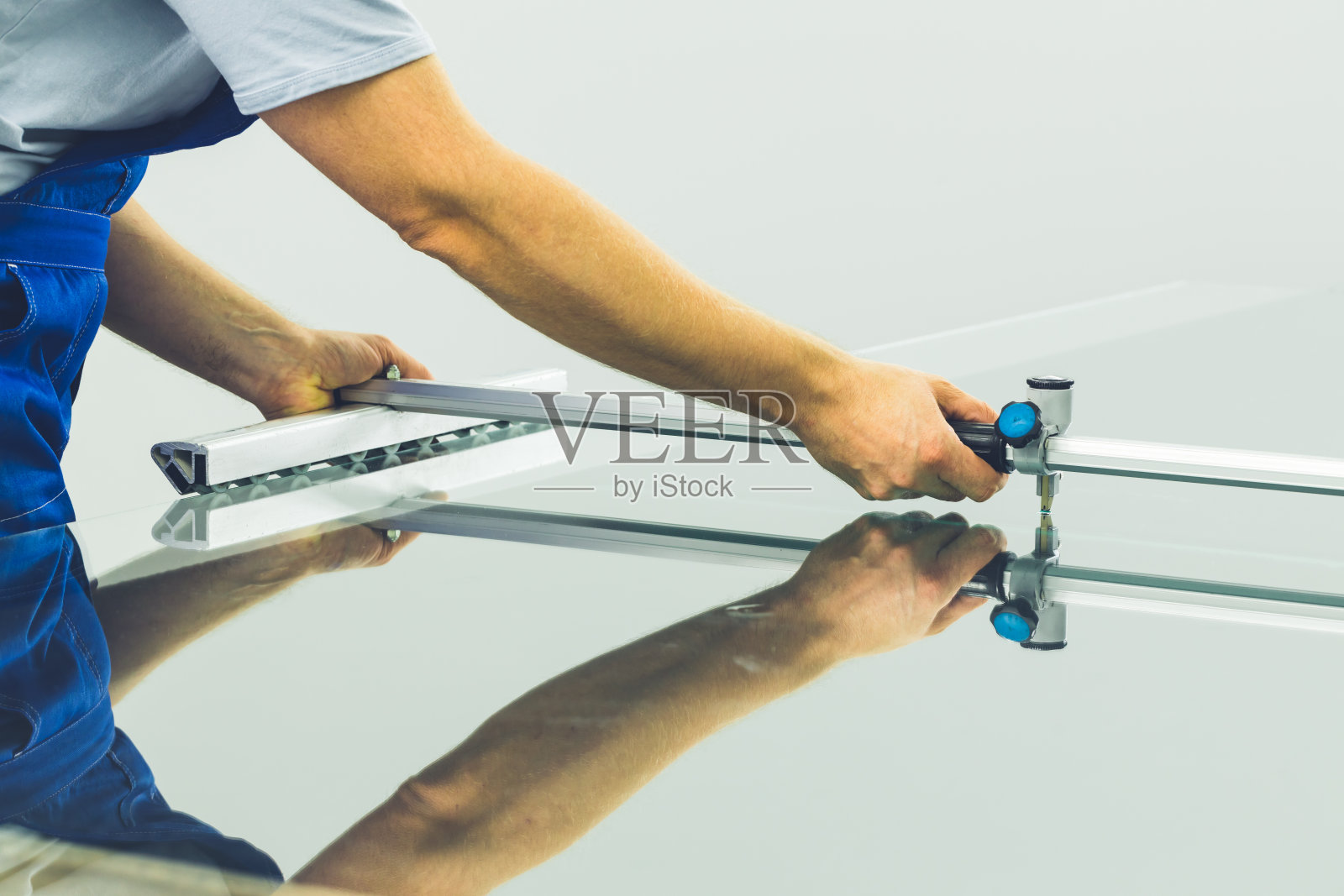 玻璃厂的一名员工用专门的设备切割玻璃照片摄影图片