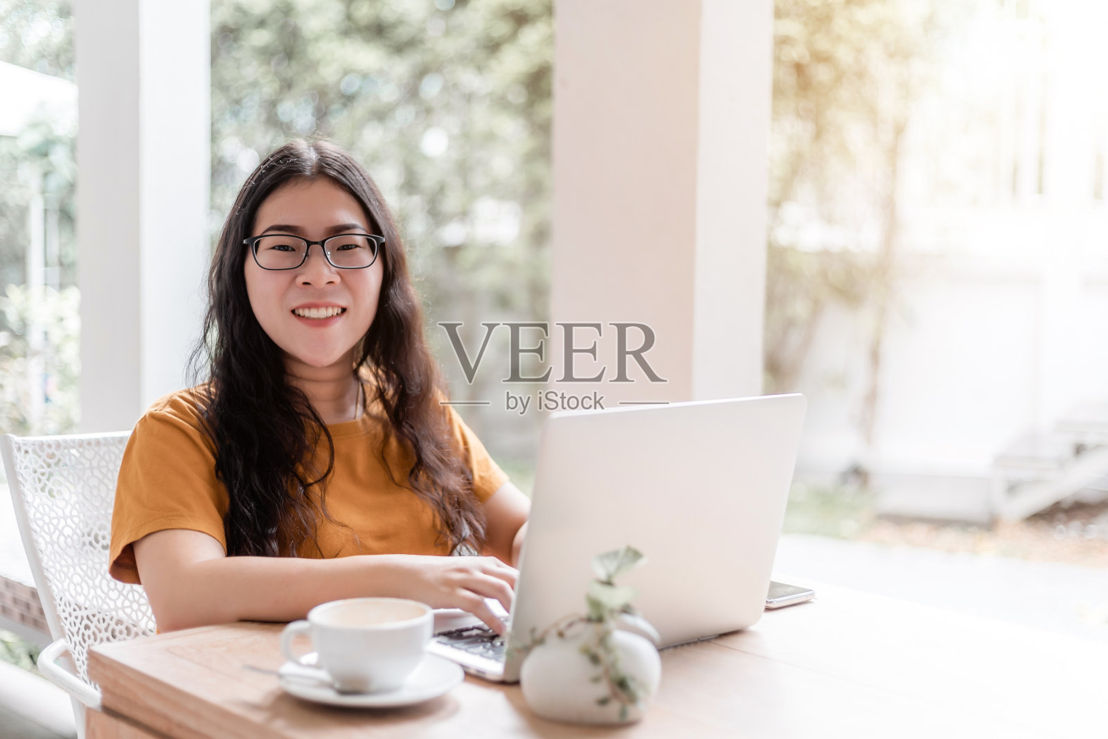 快乐的亚洲自由职业者商业女性休闲工作与笔记本电脑，咖啡杯和智能手机在咖啡馆的背景，沟通的概念照片摄影图片