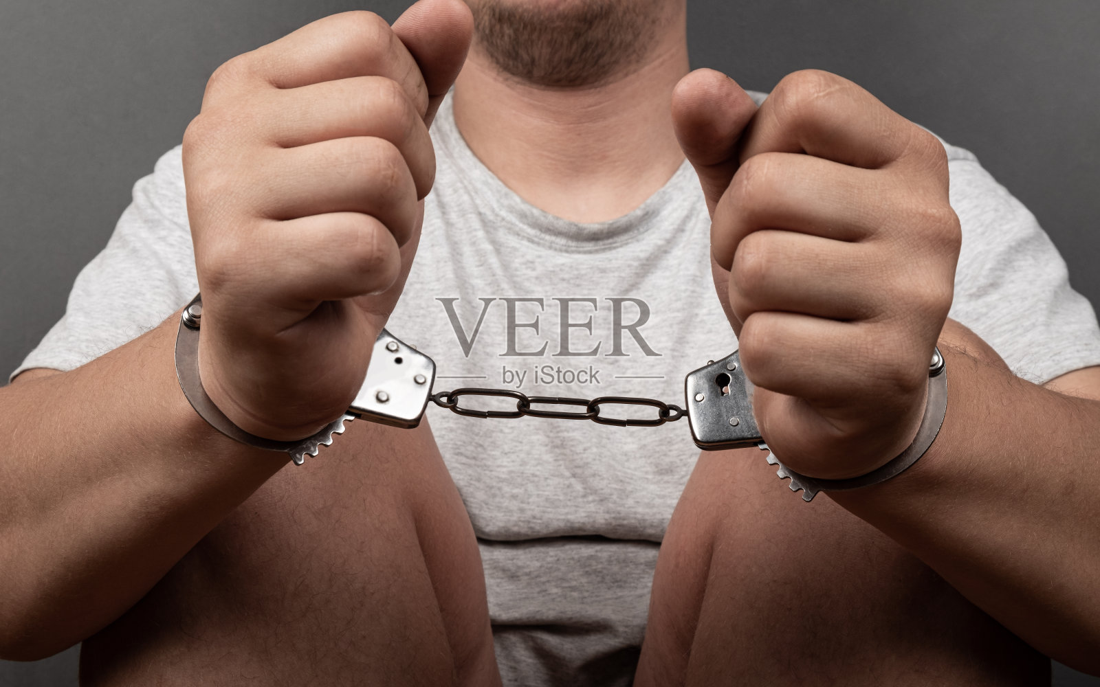 一个戴着手铐坐在地板上的人，被逮捕了照片摄影图片