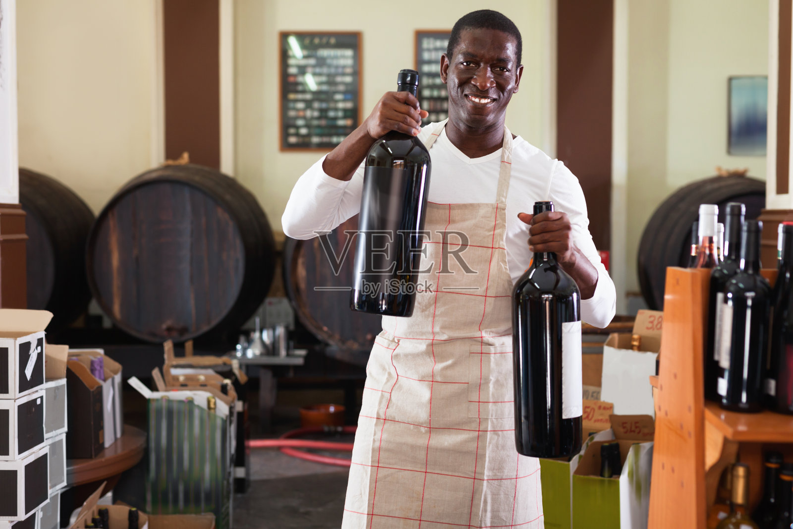 穿着围裙微笑的推销员在酒厂里向顾客敬酒照片摄影图片