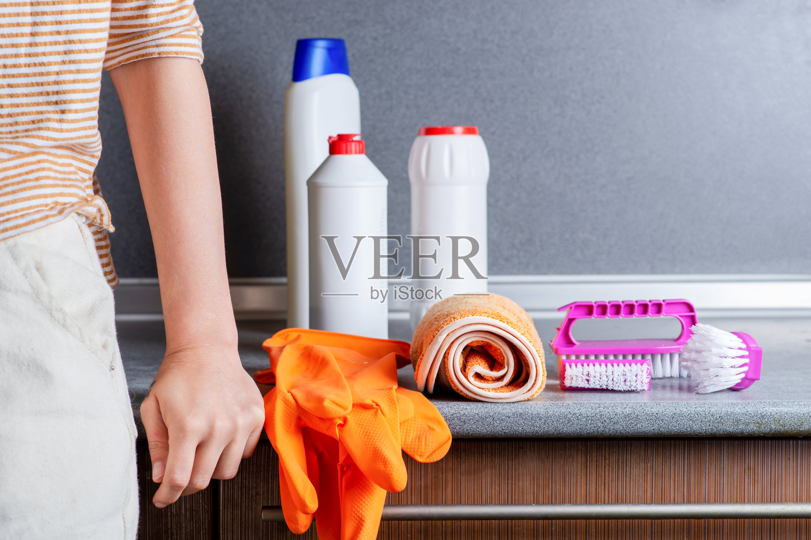 打扫厨房。厨房桌上有清洁用品，刷子，橡胶手套。一个女人的手放在桌子上。照片摄影图片