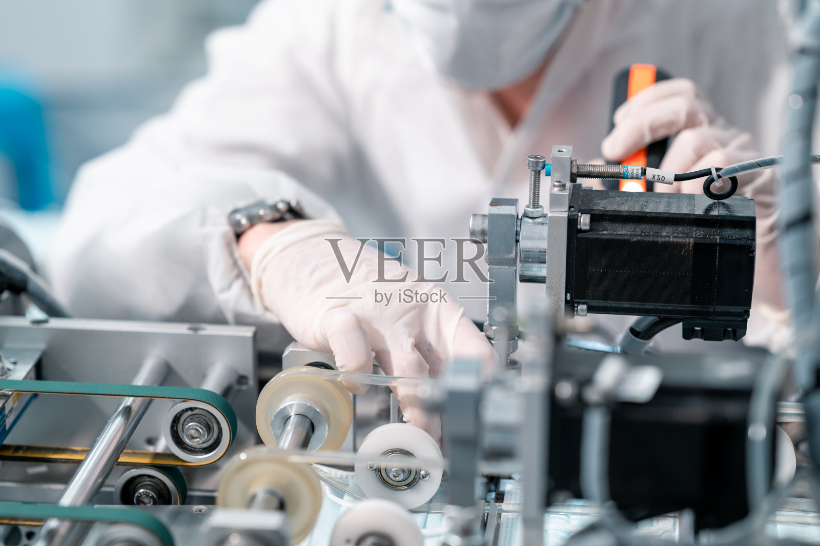 图为，穿着防护服的科学家们在工厂的实验室里检查口罩制造机器。反病毒生产仓库。安全和预防新冠肺炎的概念。照片摄影图片