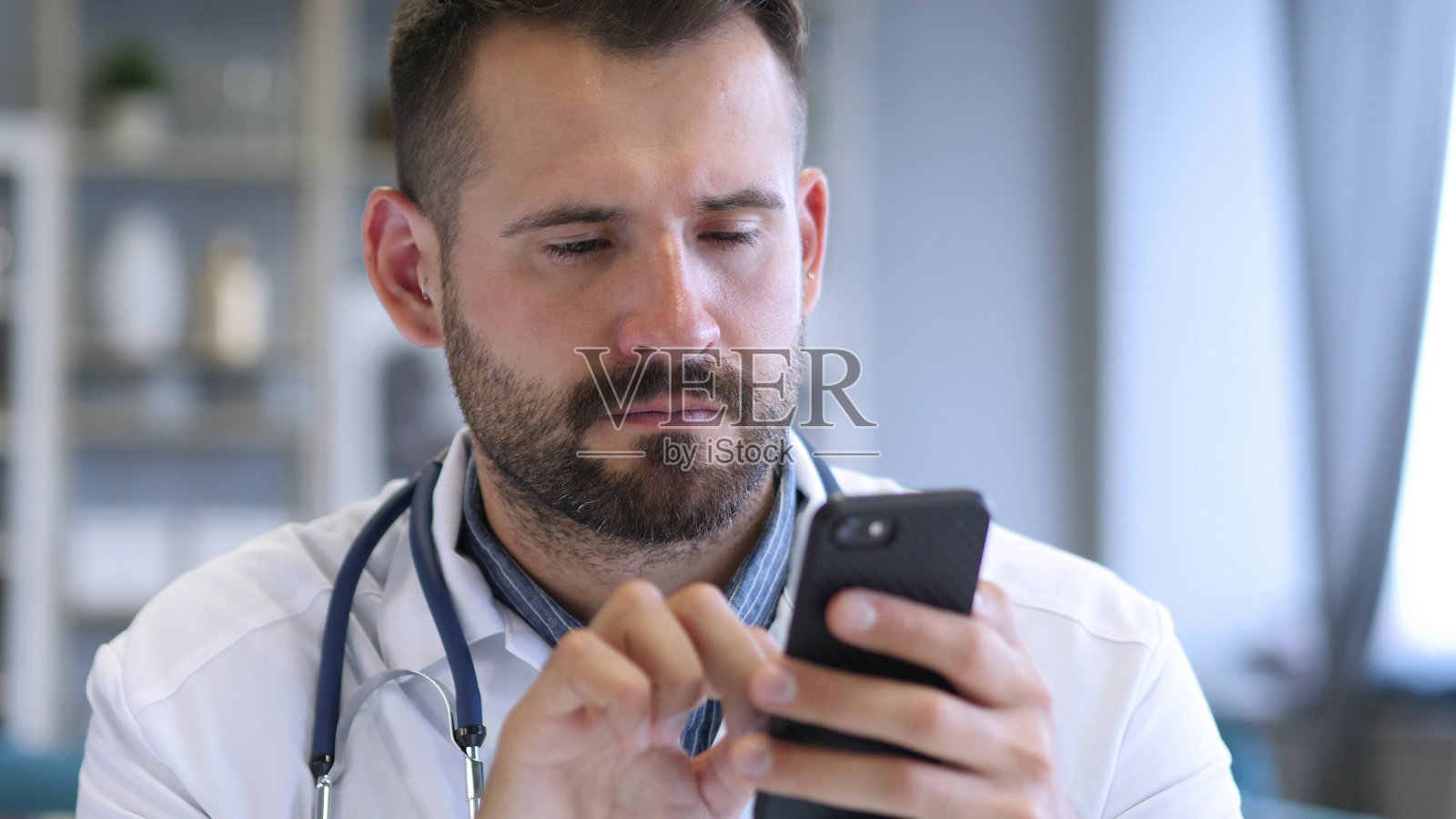 医生在智能手机上浏览照片摄影图片