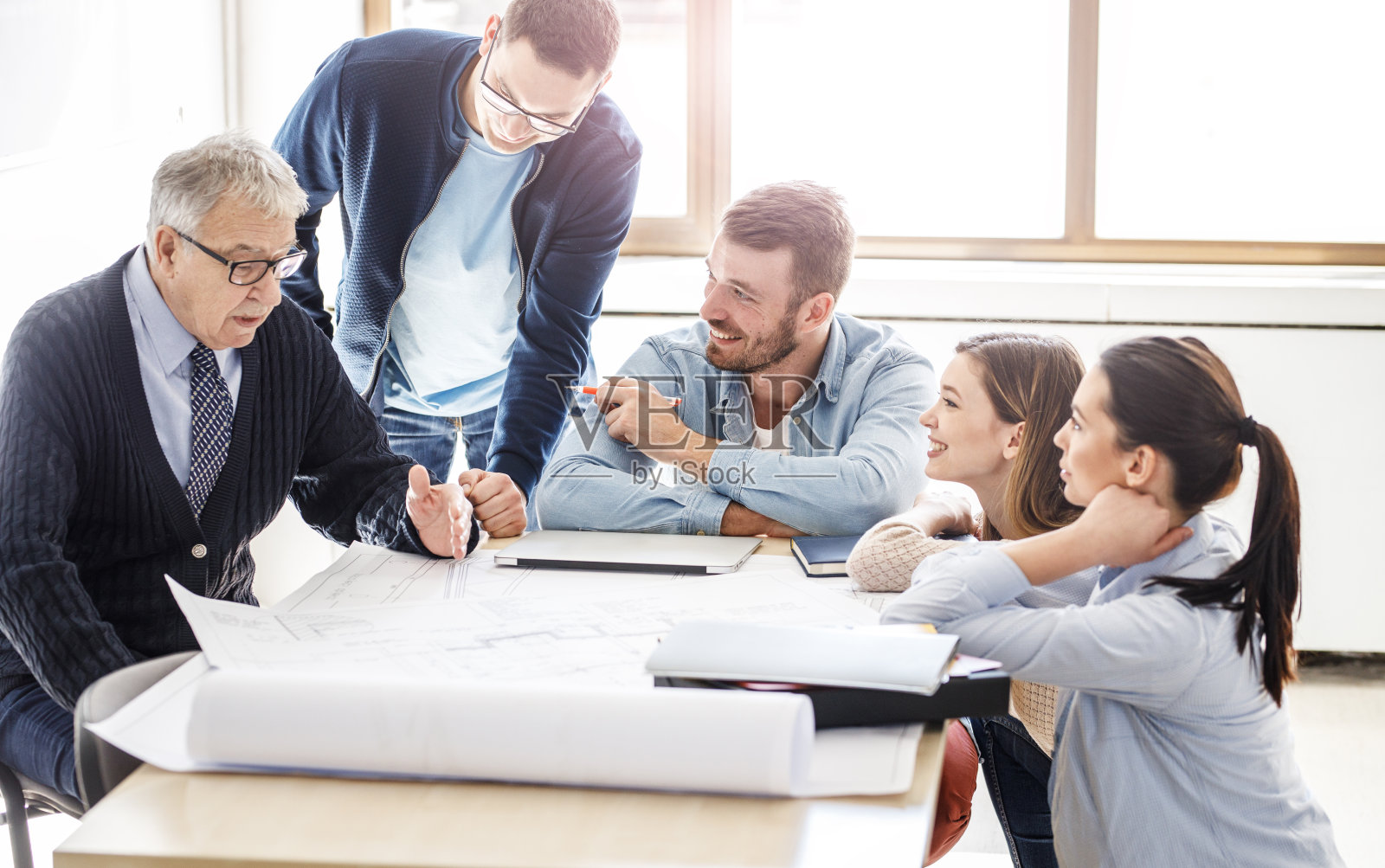 大学教授和他的学生们一起检查蓝图。照片摄影图片