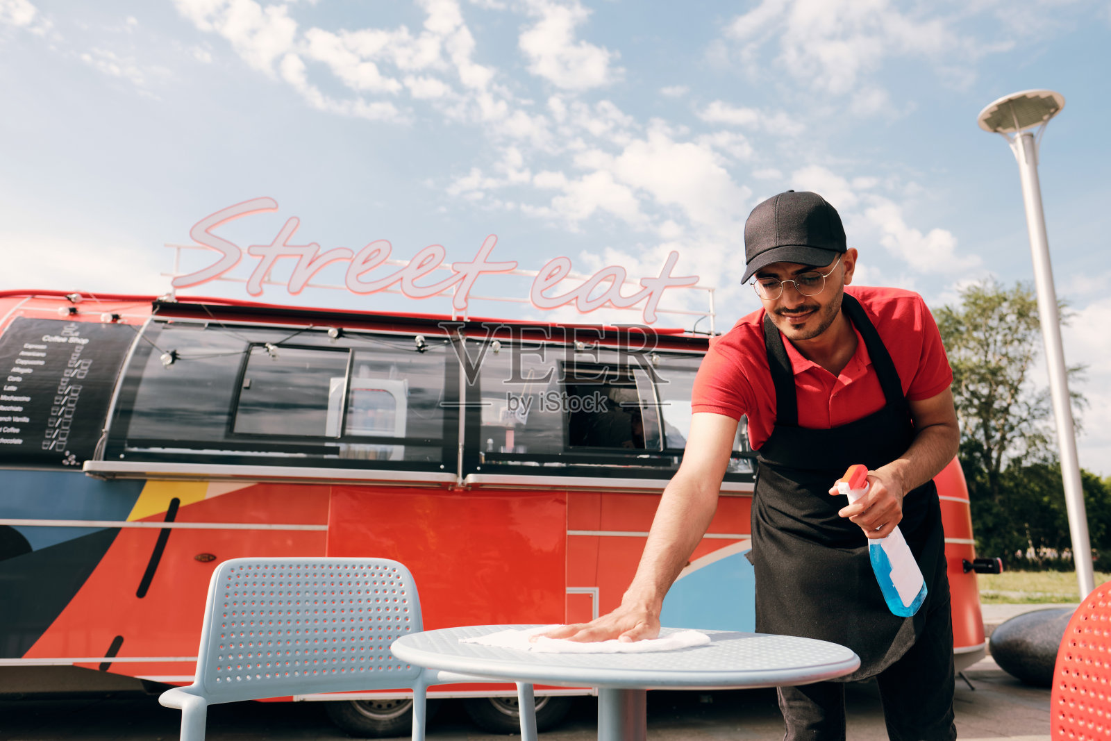 穿着制服的年轻人在塑料桌子上喷消毒剂照片摄影图片
