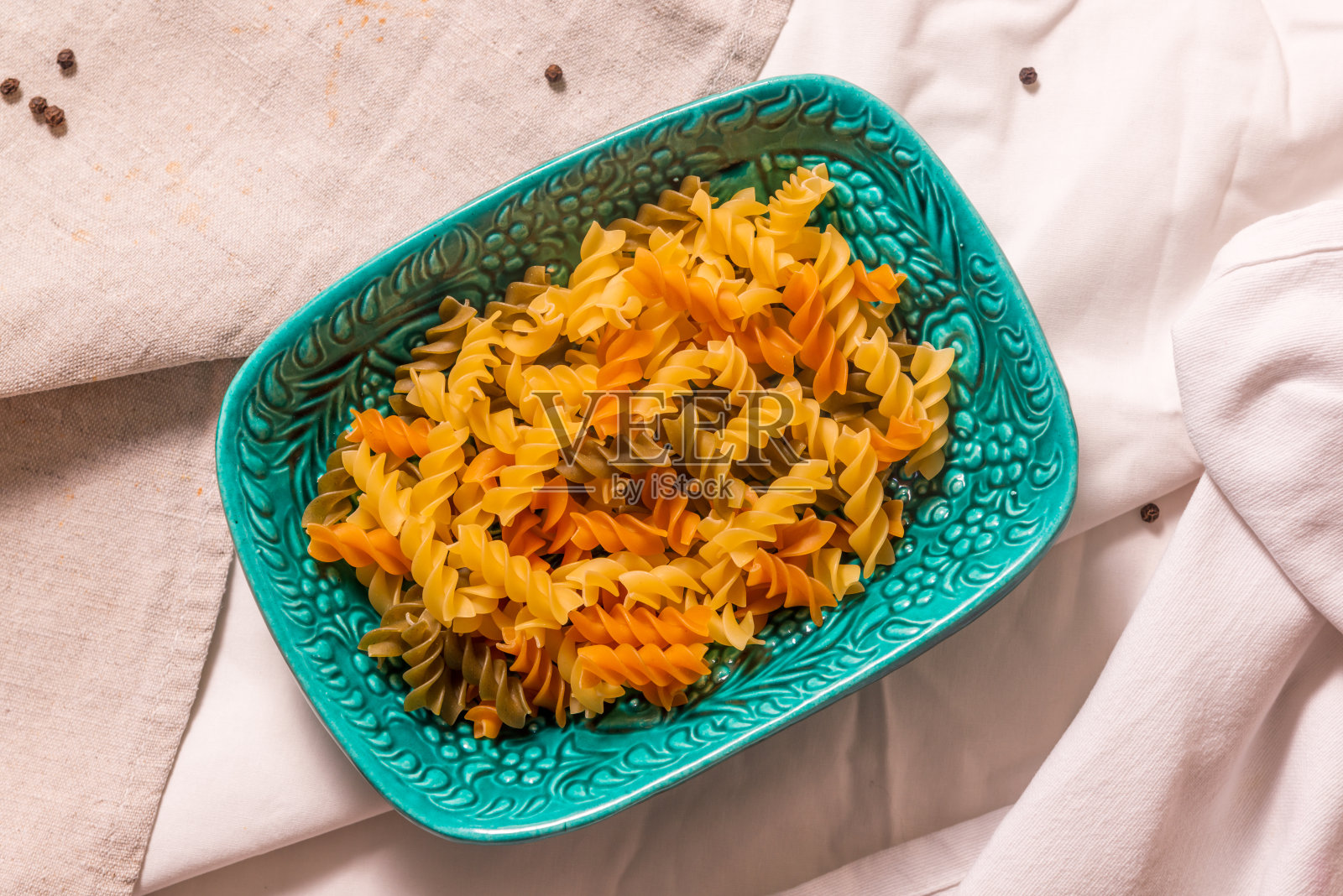 一张铺满毛巾的桌子上放着一碗绿松石色的陶瓷面食。水平的照片。照片摄影图片