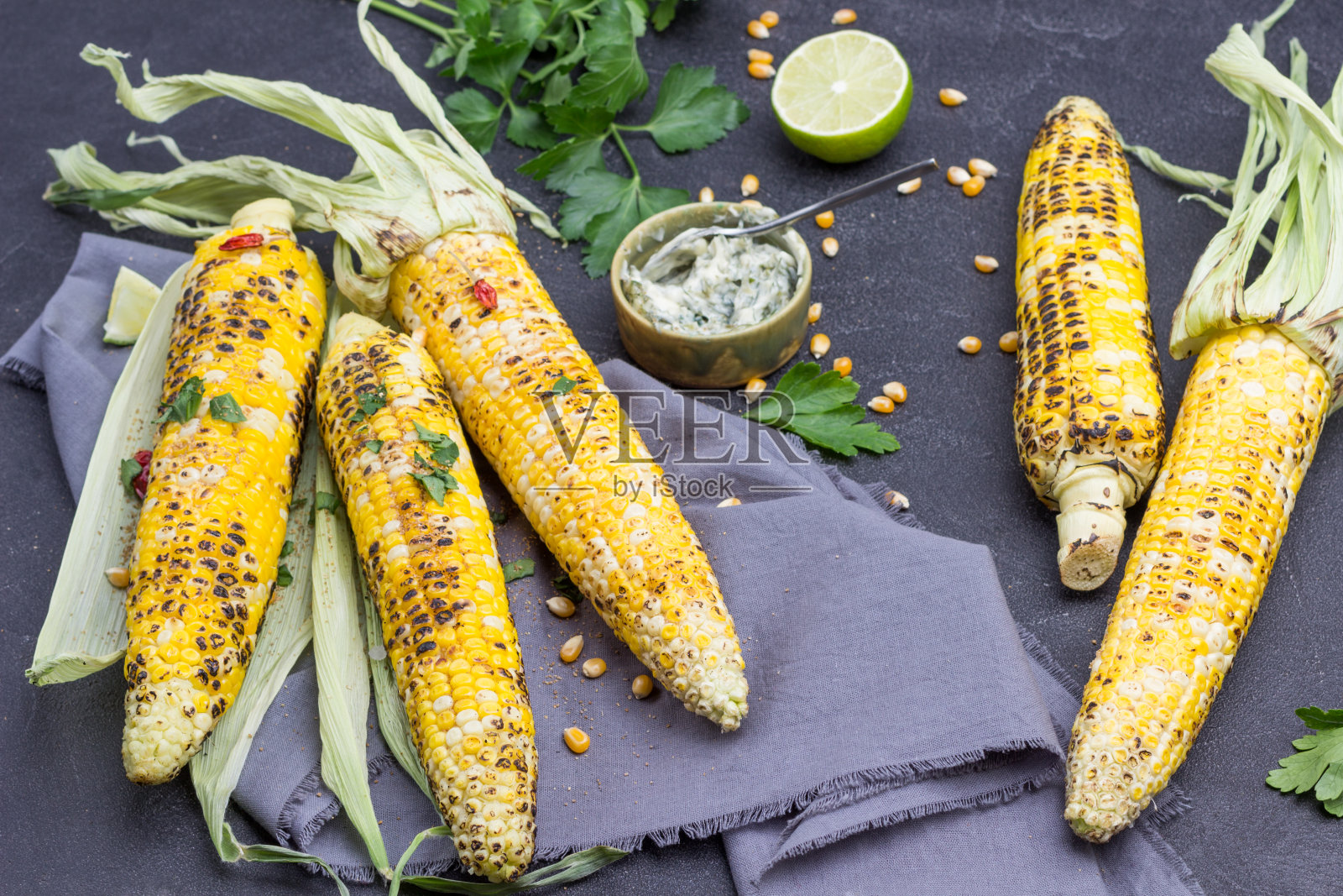 灰色餐巾上的烤玉米棒。照片摄影图片