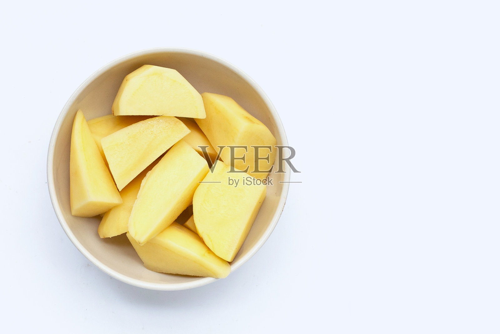 新鲜土豆切成块，放在碗里，白色的背景。照片摄影图片