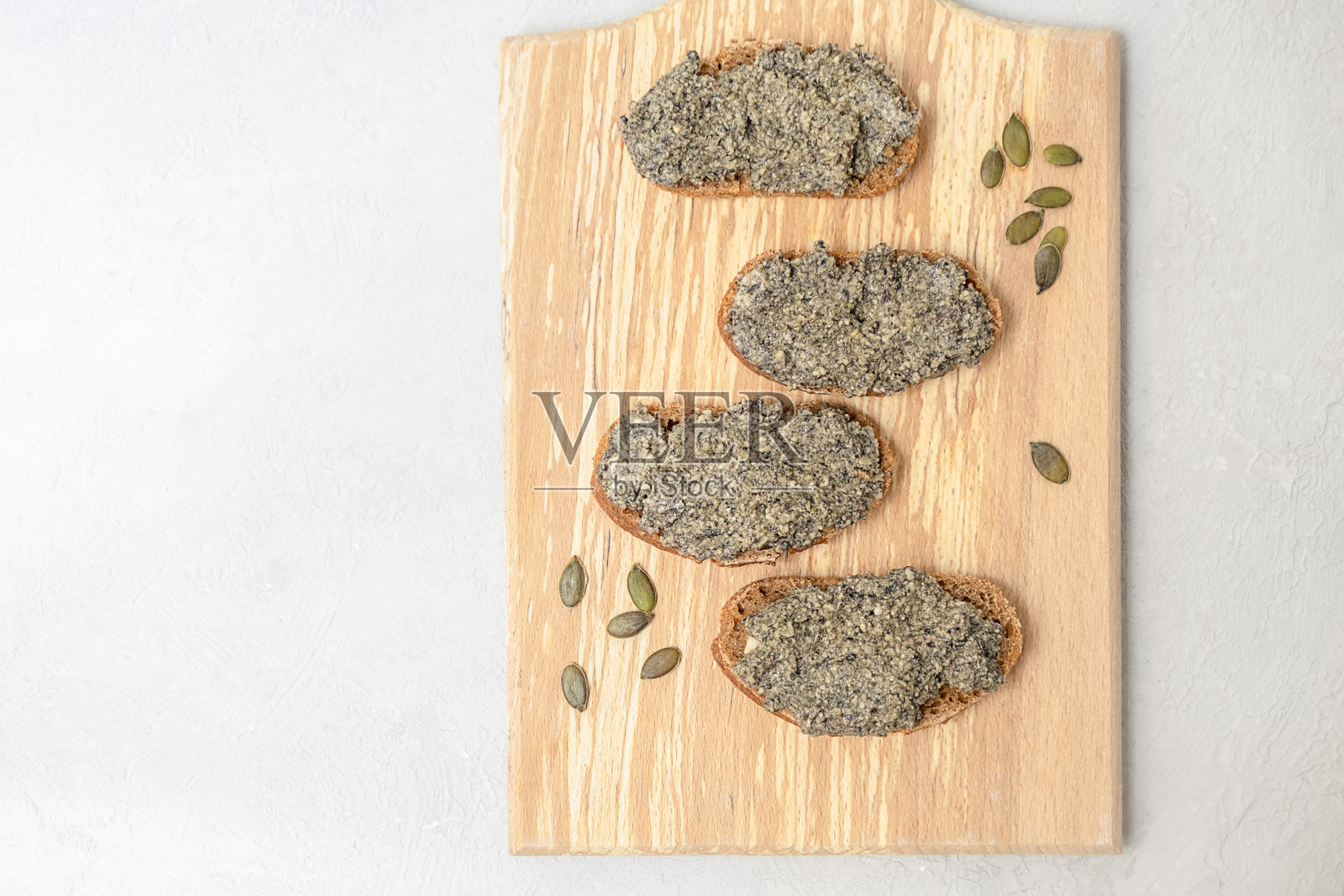 益生菌培养的素食奶酪酱，由南瓜籽铺在面包片上制成照片摄影图片