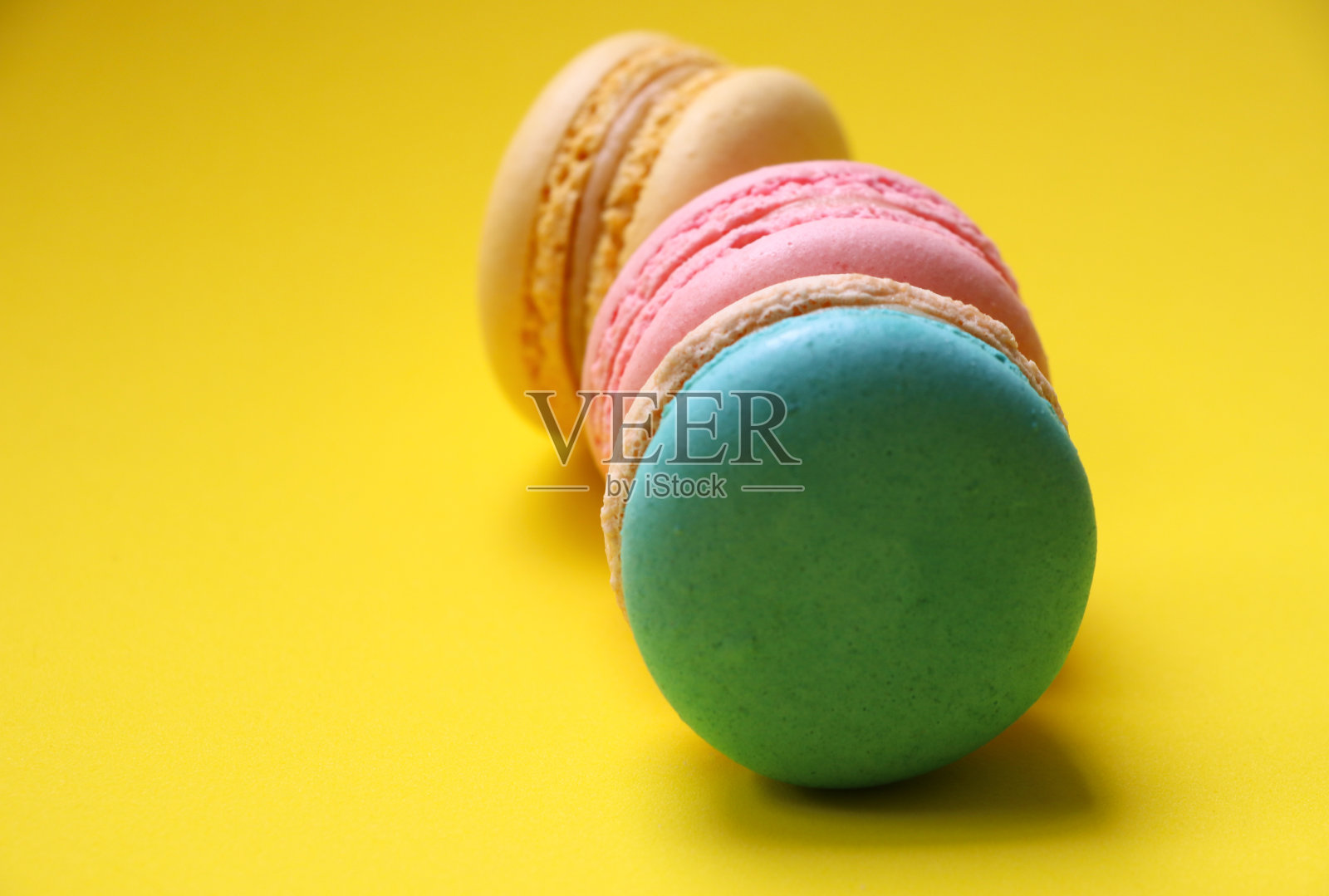 在黄色背景上选择性聚焦一组杏仁饼干，彩色点心和甜食照片摄影图片