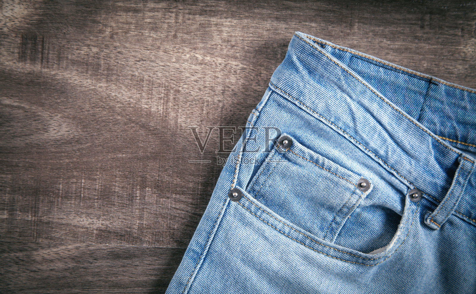 棕色木制背景上的牛仔裤。照片摄影图片