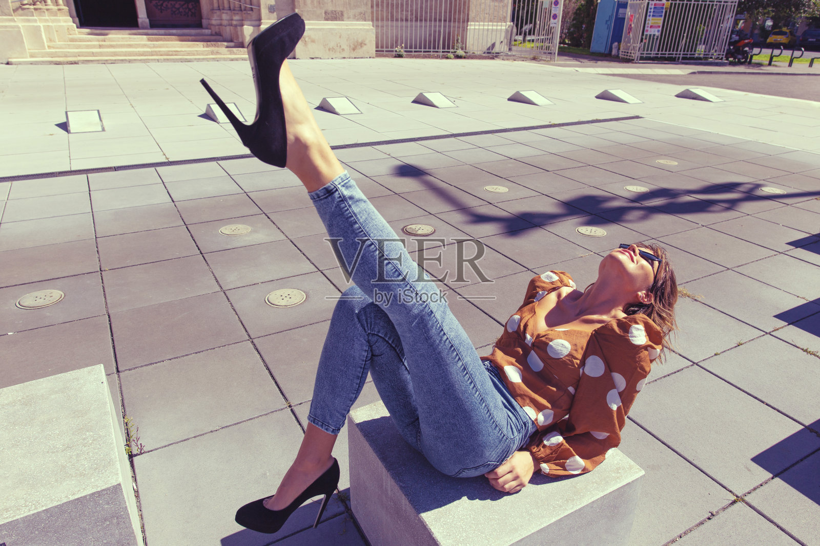 时尚的年轻女旅行者坐在石头上在城市著名的地方，腿照片摄影图片