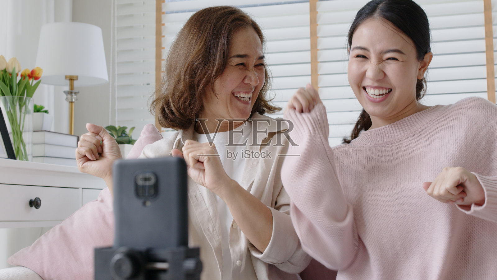 坦诚的妈妈和成年的孩子坐在家里客厅的沙发沙发上享受福利隔离自我隔离活动。家庭享受自拍拍摄记录通过互联网网络wifi连接。照片摄影图片