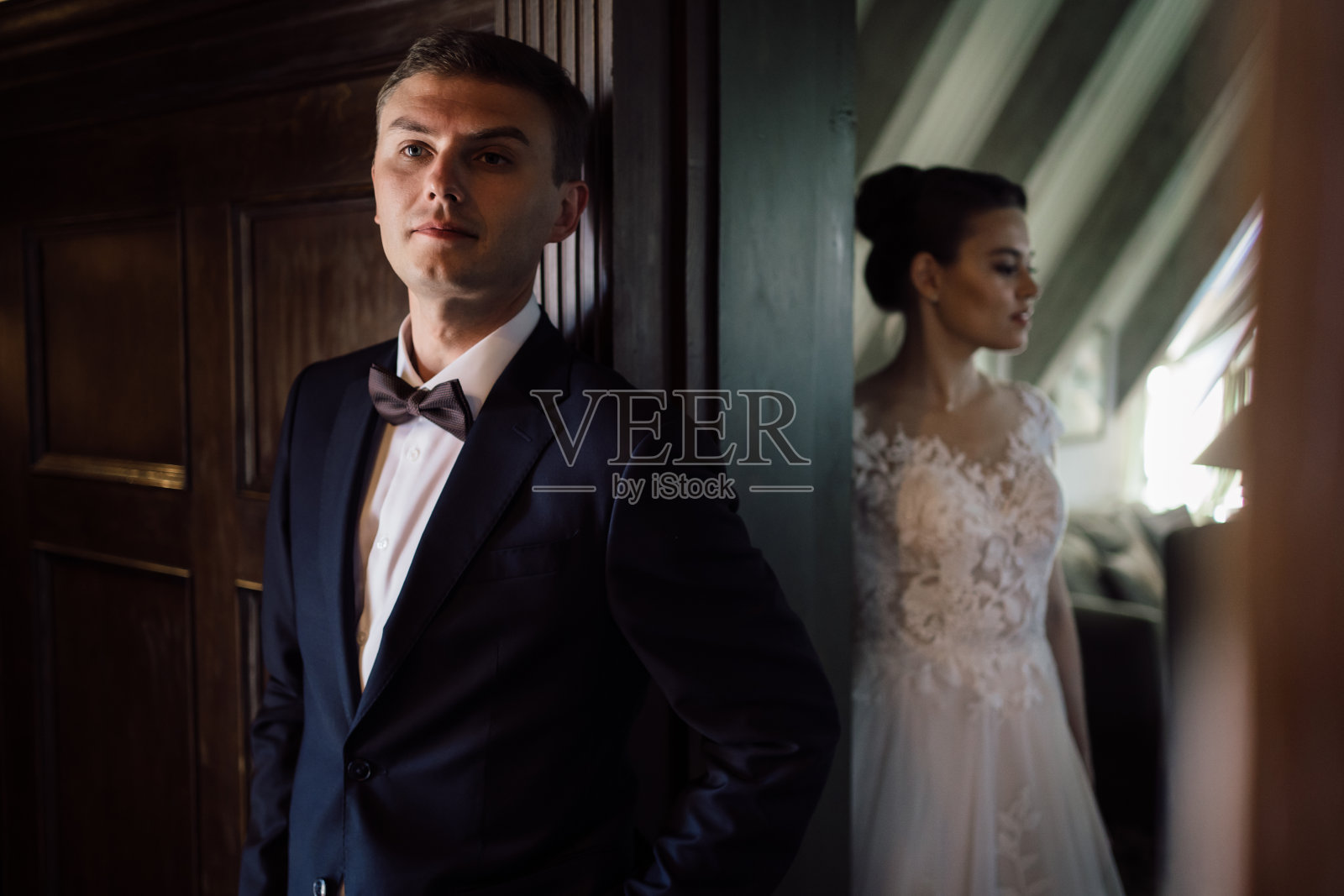 第一次见面前，新娘和新郎隔着墙在门口交谈照片摄影图片