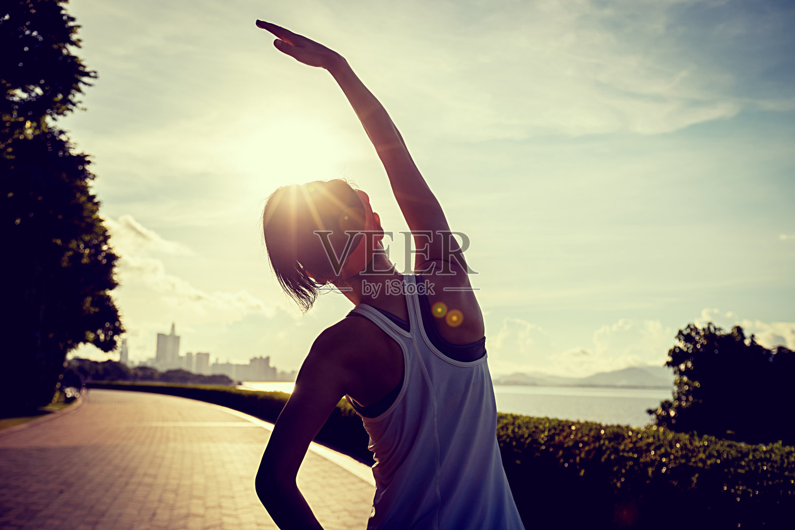 健身女人在阳光明媚的热带海边暖身照片摄影图片