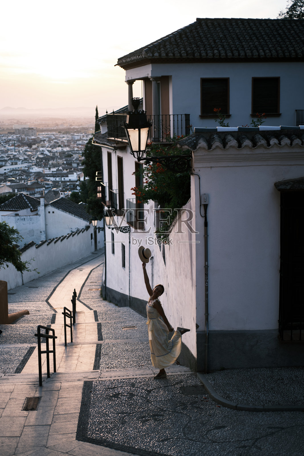 一个身穿黄色衣服，头戴帽子的年轻女子走在格拉纳达的街道上照片摄影图片