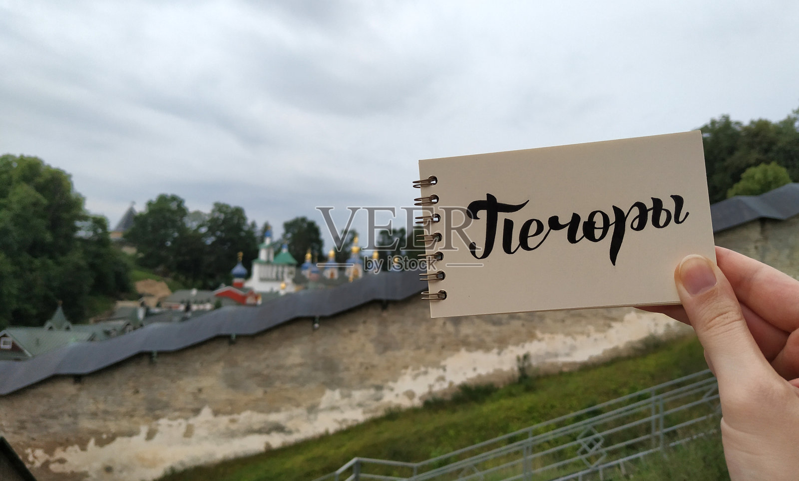 View to Pskov-Pechory Orthodox male Monastery with calligraphy题字“Pechory”in russian on notebook。俄罗斯普斯科夫州佩霍里，2021年7月30日。——在笔记本上。移动摄影。照片摄影图片