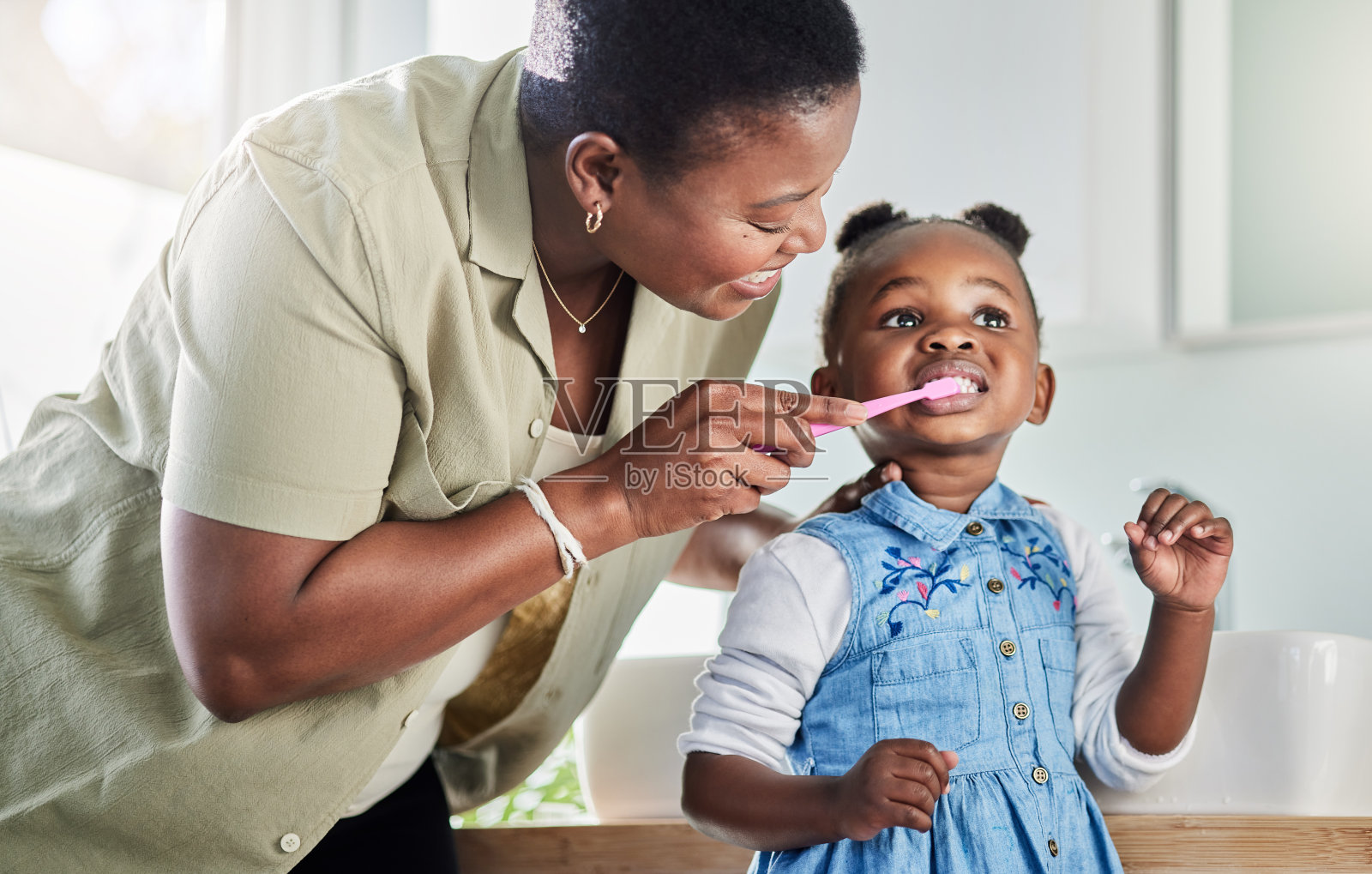图为一位母亲在家里的浴室里给她的小女儿刷牙照片摄影图片