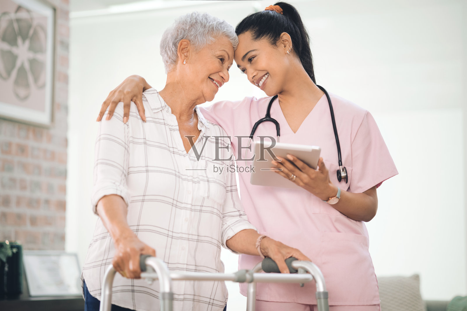 一位老妇人使用助行器，在理疗师的帮助下行走照片摄影图片