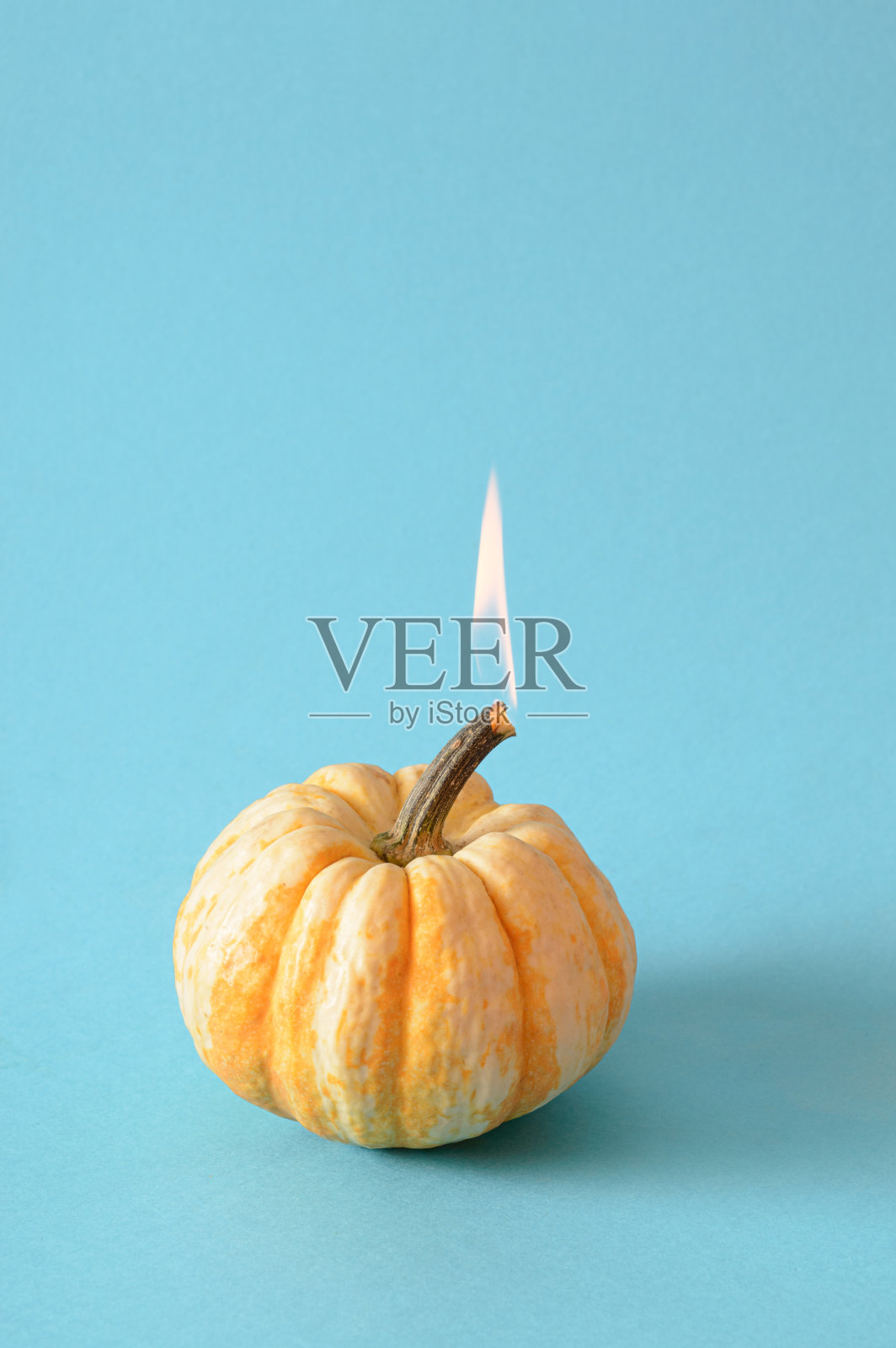 一个燃烧的南瓜是万圣节的最小概念。创意秋假日蓝色背景照片摄影图片
