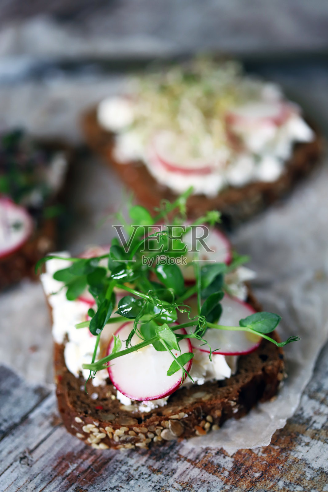 打开三明治，加入白奶酪，萝卜和蔬菜。照片摄影图片
