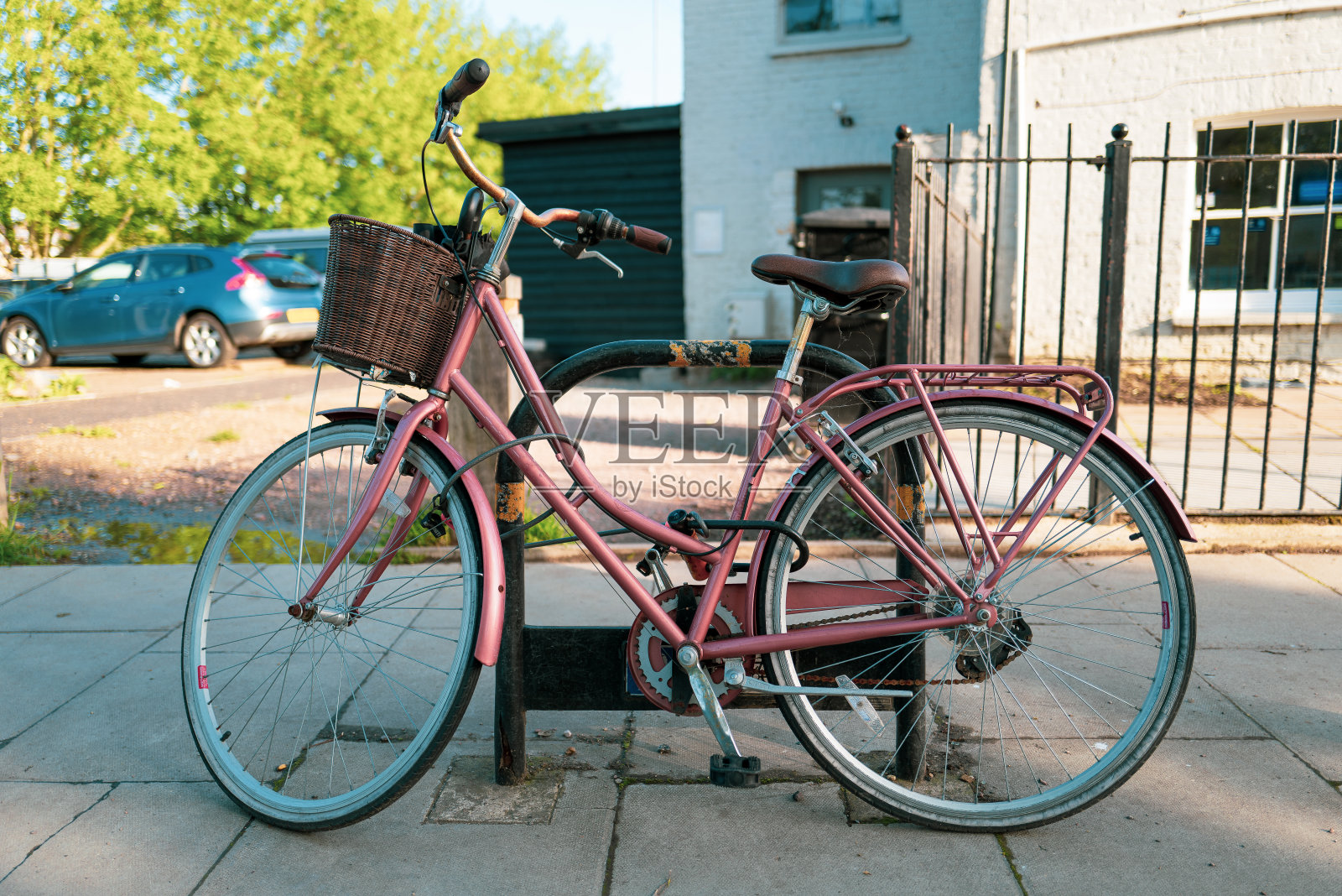 粉红色的自行车和篮子停在城市的街道上照片摄影图片